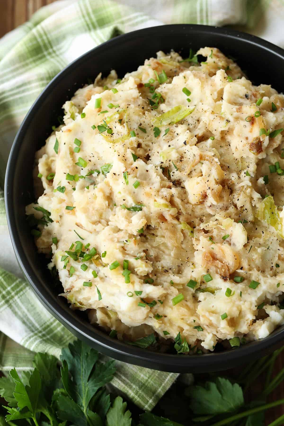This Colcannon recipe is a St. Patrick's Day favorite! Creamy, buttery mashed potatoes blended with sweet caramelized onions and cabbage. mashed potatoes with cabbage and onions in black bowl with napkin