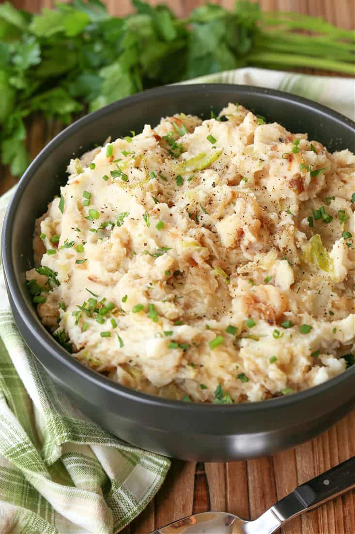 Mashed potatoes with caramelized onions and cabbage topped with chives in a bowl.