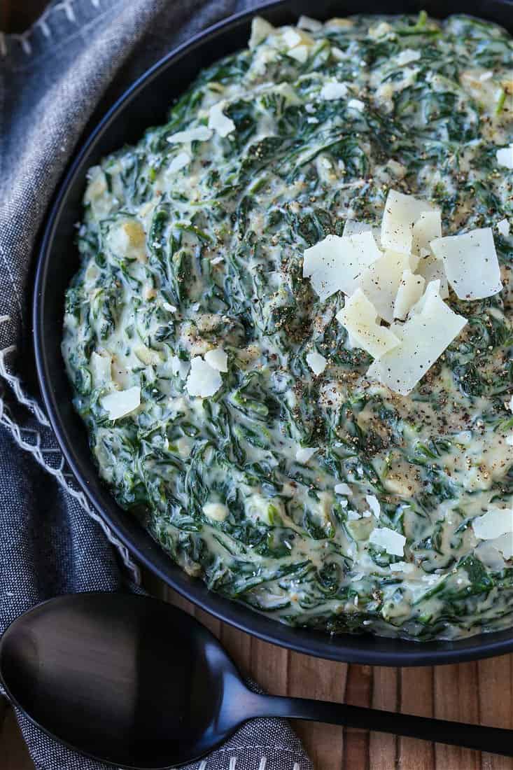 Creamed Spinach in a black bowl with parmesan cheese