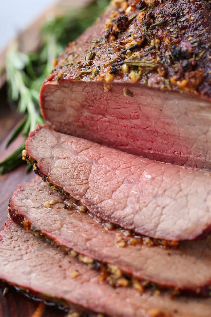 Roast beef with garlic and rosemary sliced on a board