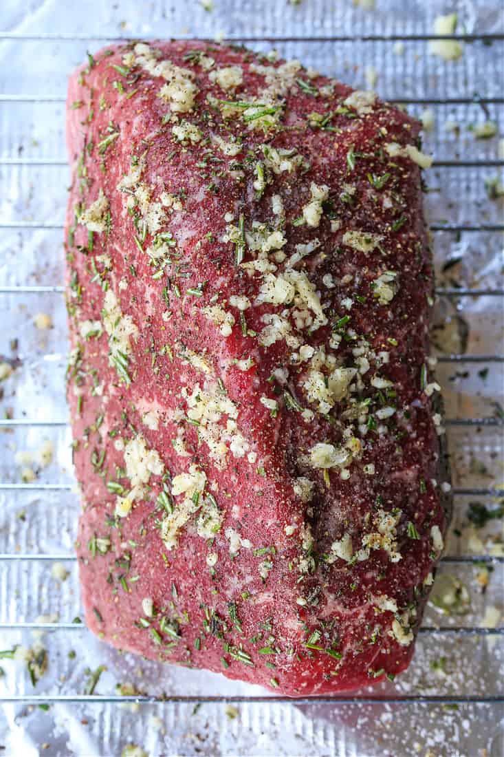 Roast beef on a baking rack with garlic and herbs