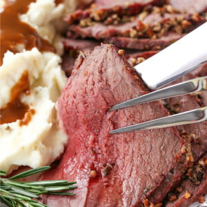 slice of rare roast beef held up with serving fork and knife