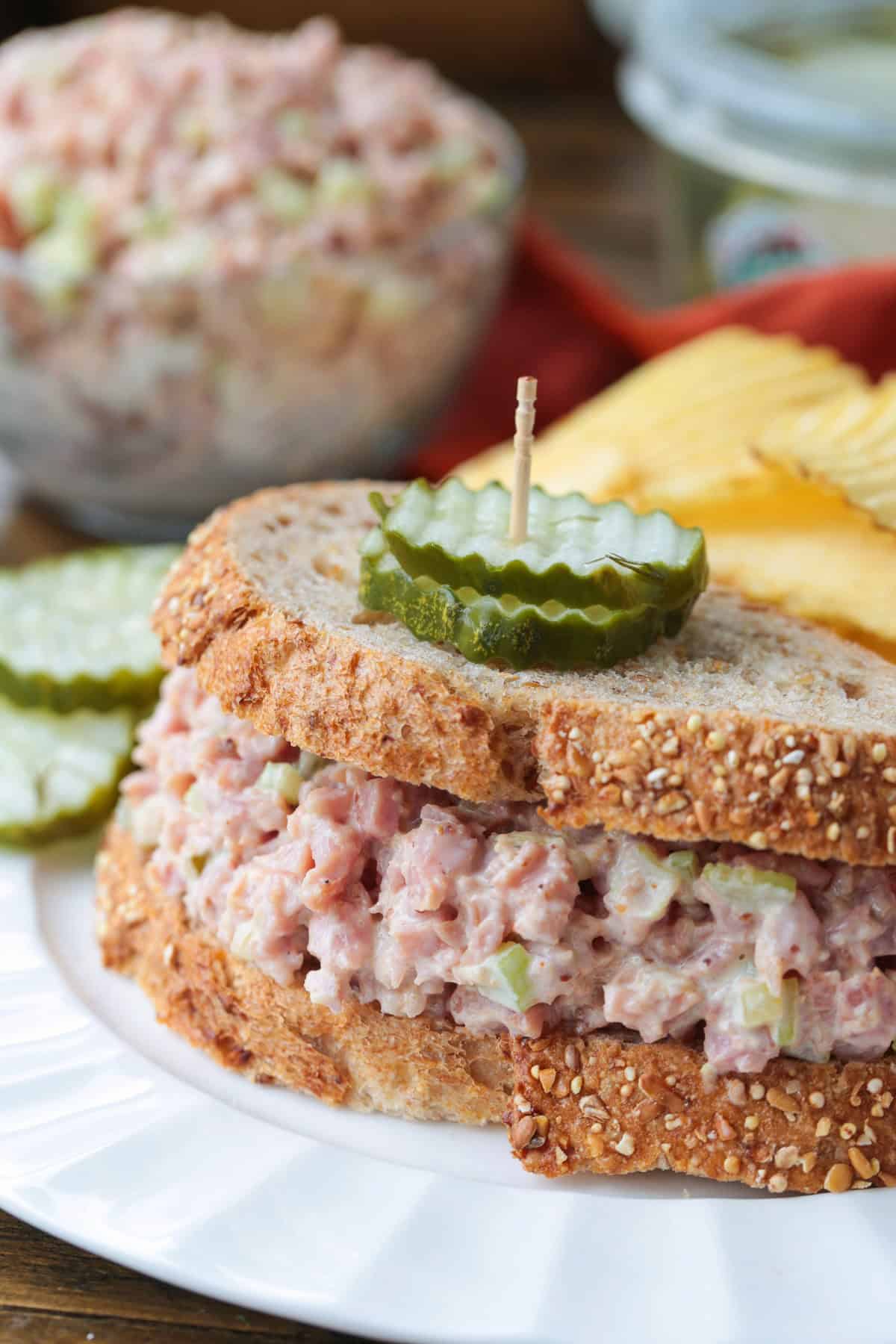 Our Ham salad recipe is the perfect way to use up leftover ham! Creamy and tangy, it’s great for sandwiches, wraps, or served with crackers. sandwich with ham salad topped with pickles
