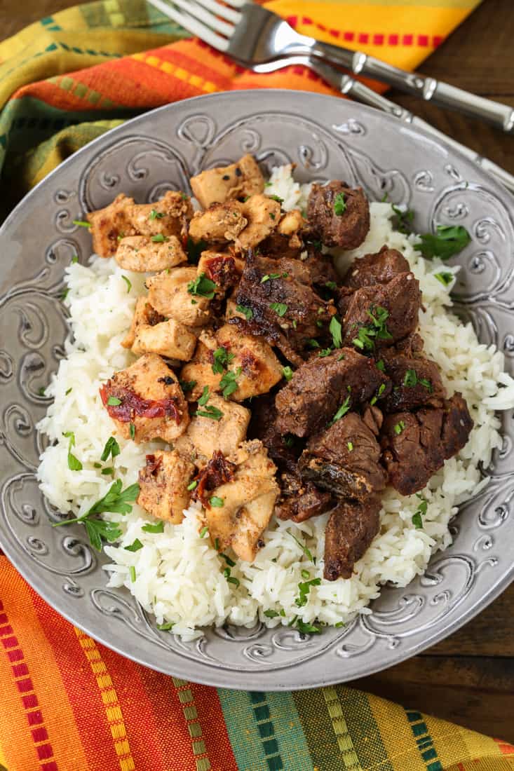 Marinated chicken and steak in a bowl with rice