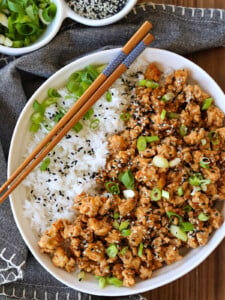 sesame ground chicken in a bowl with rice and chopsticks