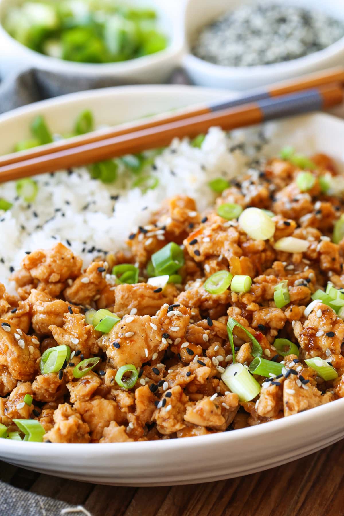sesame ground chicken in bowl from the side with rice and chopsticks 