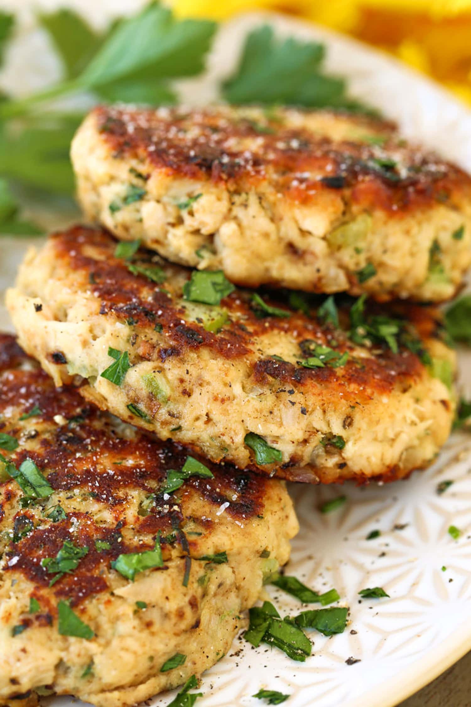 Tuna cakes stacked on a white plate with parsley