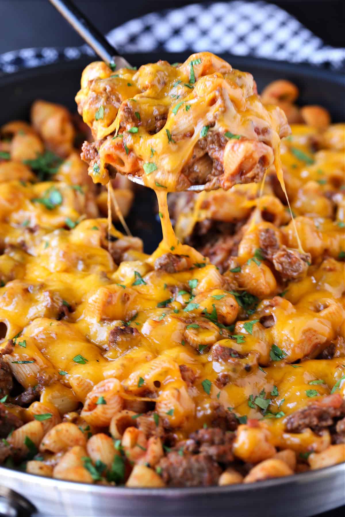 Get ready to dive into this creamy, beefy, cheesy Cheeseburger Pasta! The ultimate comfort food dinner that's ready in under 30 minutes! cheeseburger pasta in skillet with scoop on serving spoon