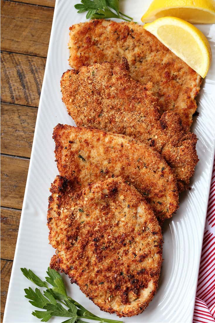 Breaded Turkey cutlets on a platter with lemon wedge