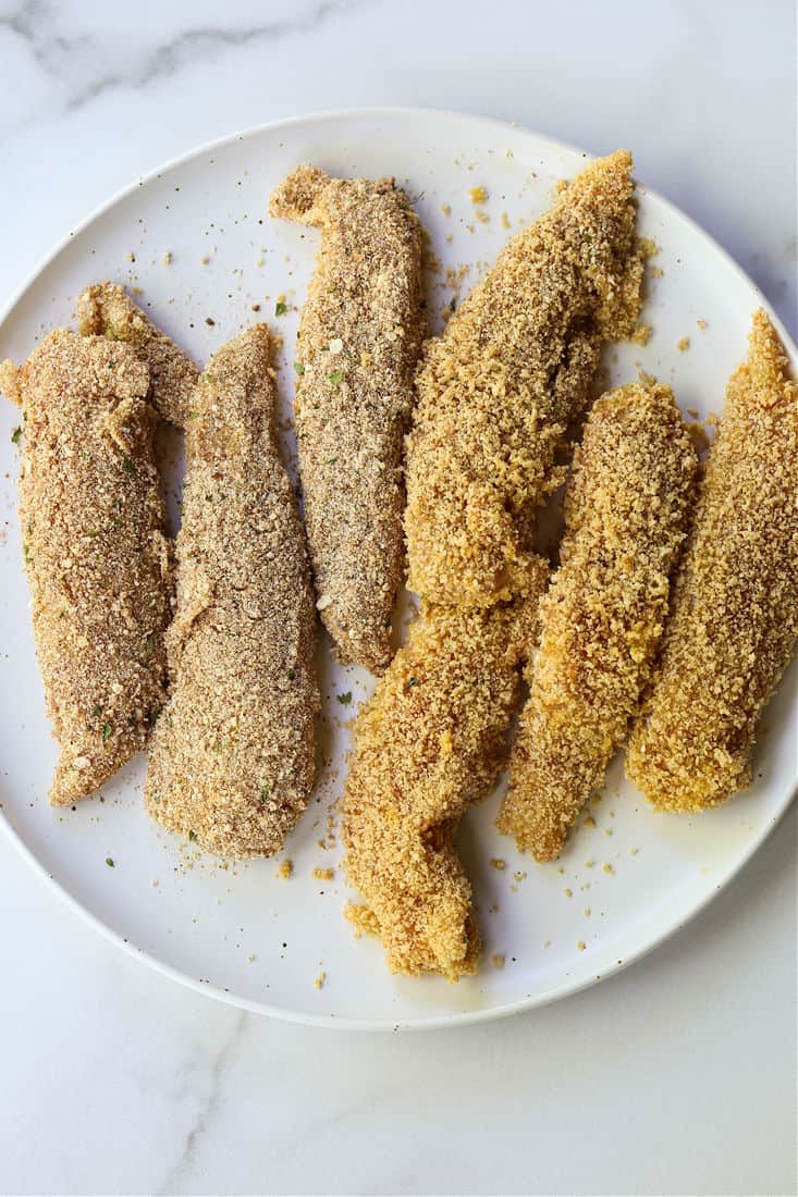These Air Fryer Chicken Tenders are so crispy on the outside and juicy on the inside! Make in large batches and then freeze for an easy meal! Breaded chicken tenders on a plate before cooking