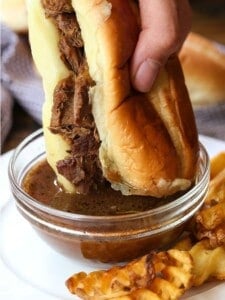 French Dip Sandwich dipping into au jus gravy
