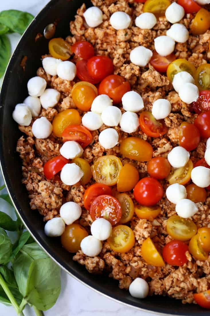 Ground chicken recipe in a skillet with mozzarella cheese and tomatoes