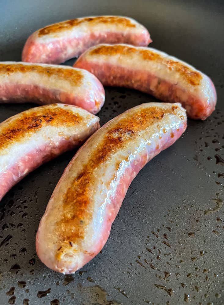 Italian sausages browning in a skillet