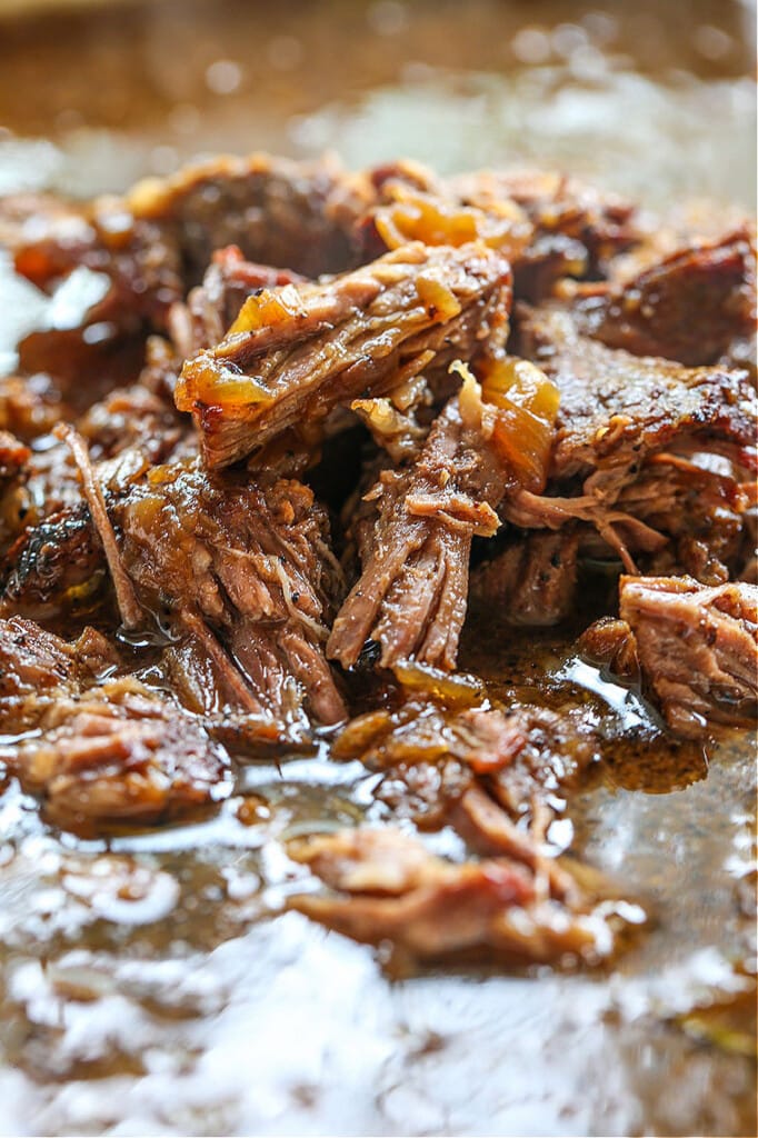 Make these Slow Cooker French Dip Sandwiches for parties or easy dinner nights! Tender, shredded beef with an au jus gravy for dipping! shredded beef in au jus gravy