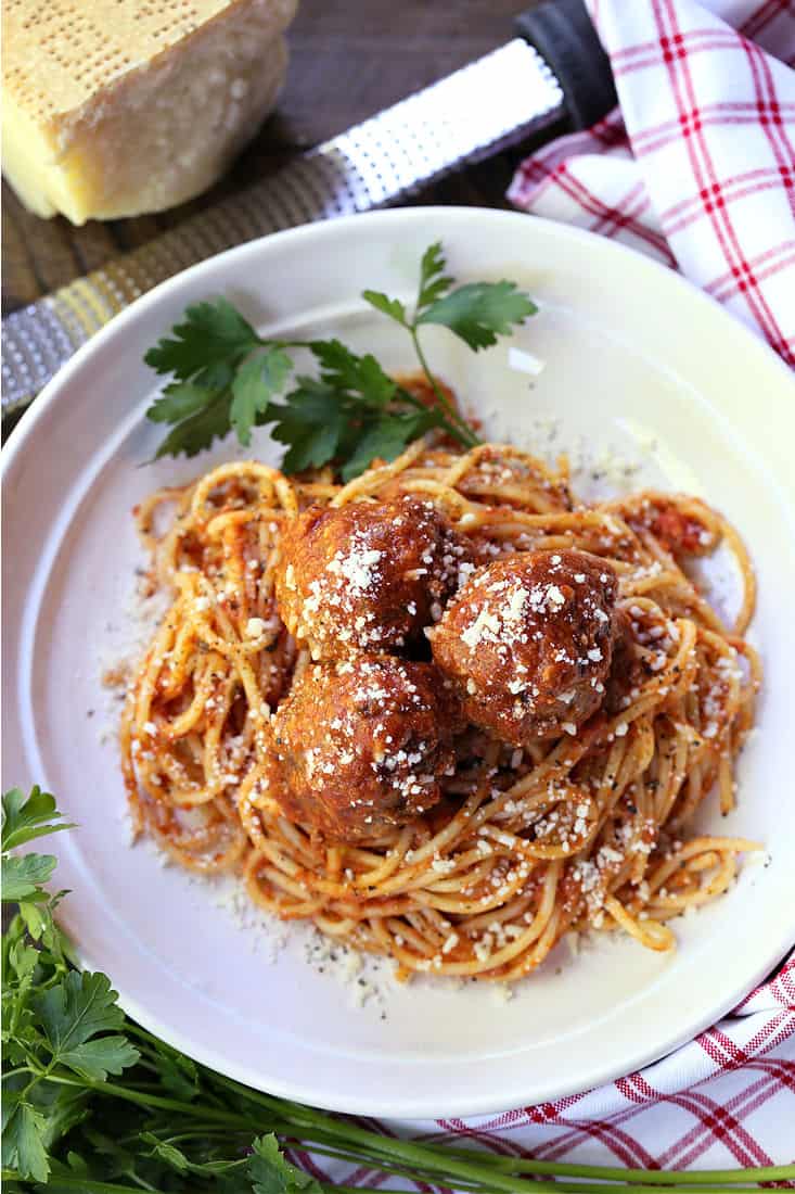 Spaghetti and meatballs on a white plate with parlsey