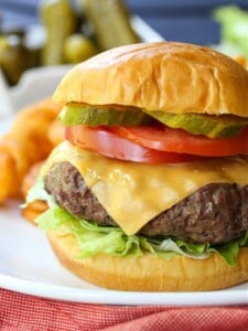 cheeseburger with toppings and fries in background