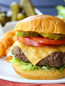 cheeseburger with toppings and fries in background