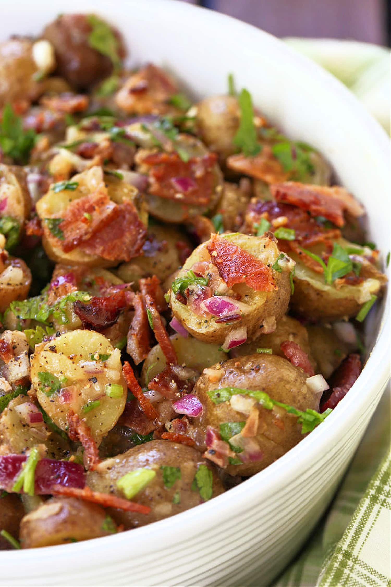 This Warm German Potato Salad is a classic party side! A no-mayo potato salad with tender potatoes, crispy bacon and a warm vinaigrette! close up of potato salad with bacon