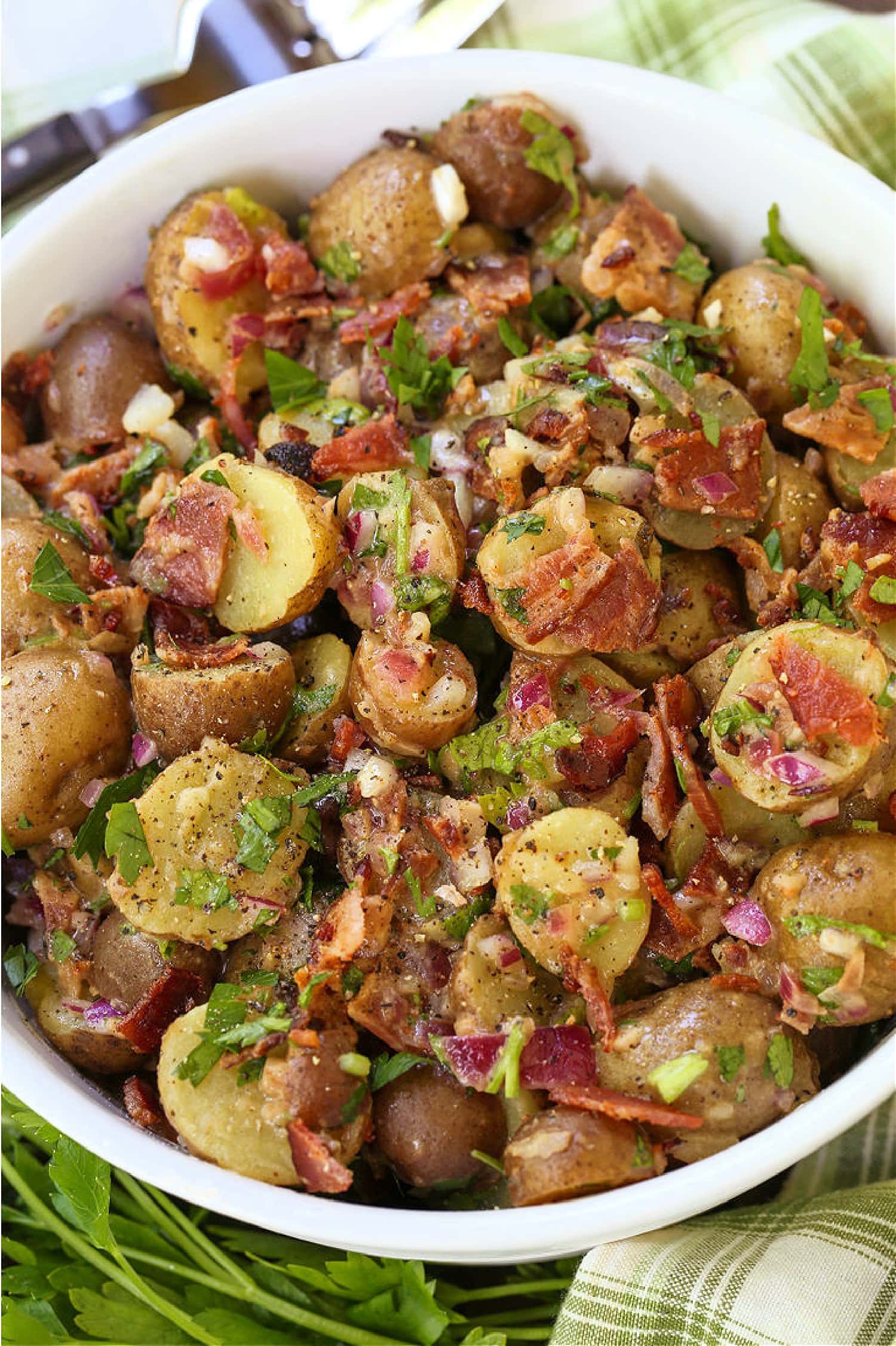 This Warm German Potato Salad is a classic party side! A no-mayo potato salad with tender potatoes, crispy bacon and a warm vinaigrette! german potato salad in white bowl