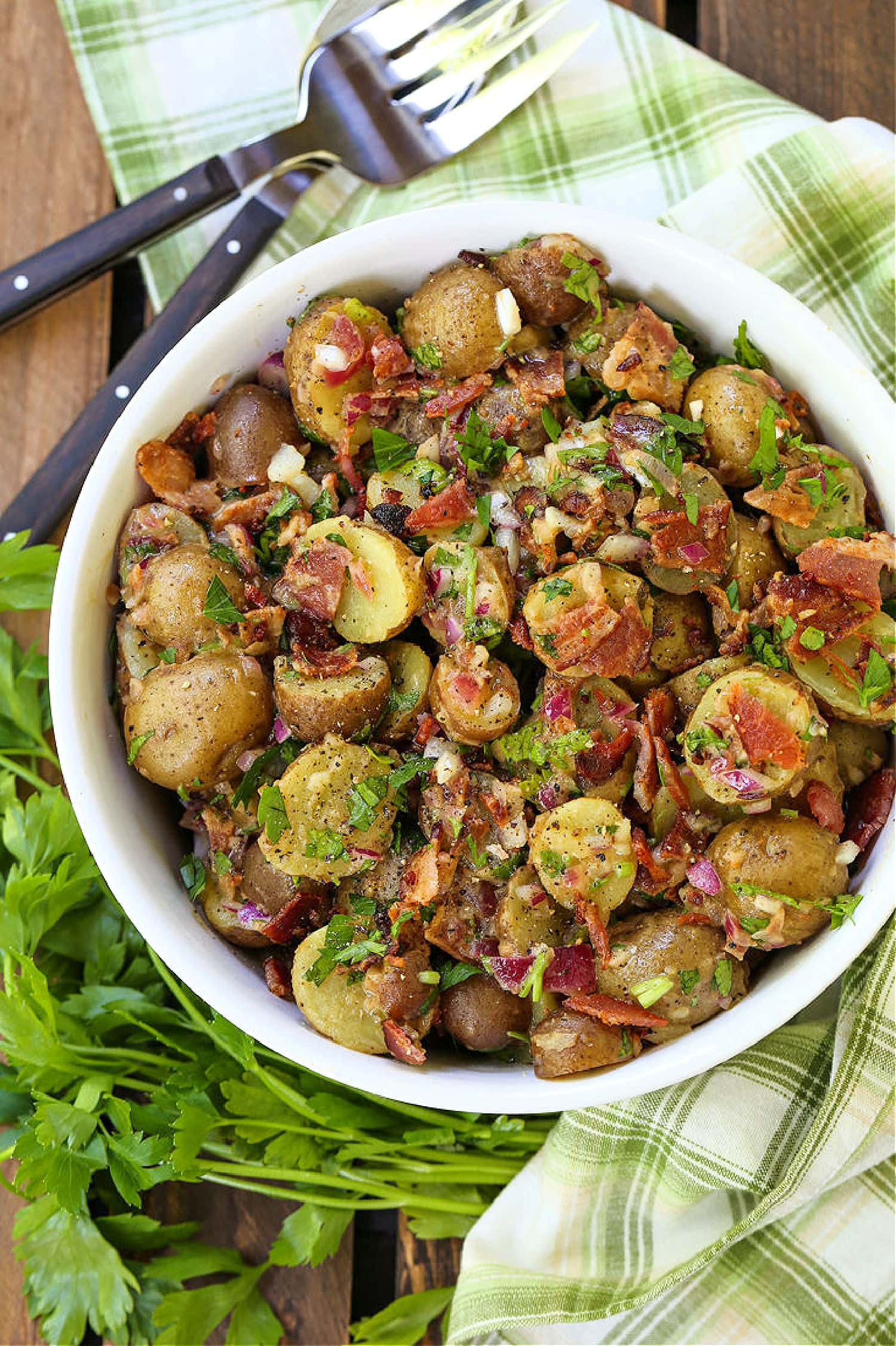 This Warm German Potato Salad is a classic party side! A no-mayo potato salad with tender potatoes, crispy bacon and a warm vinaigrette! german potato salad in bowl with fork and spoon