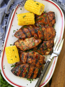 grilled chicken breasts on a platter with corn