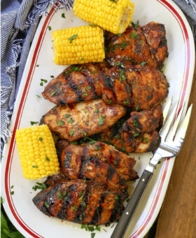 grilled chicken breasts on a platter with corn