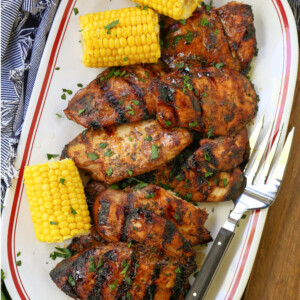 grilled chicken breasts on a platter with corn