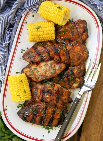 grilled chicken breasts on a platter with corn