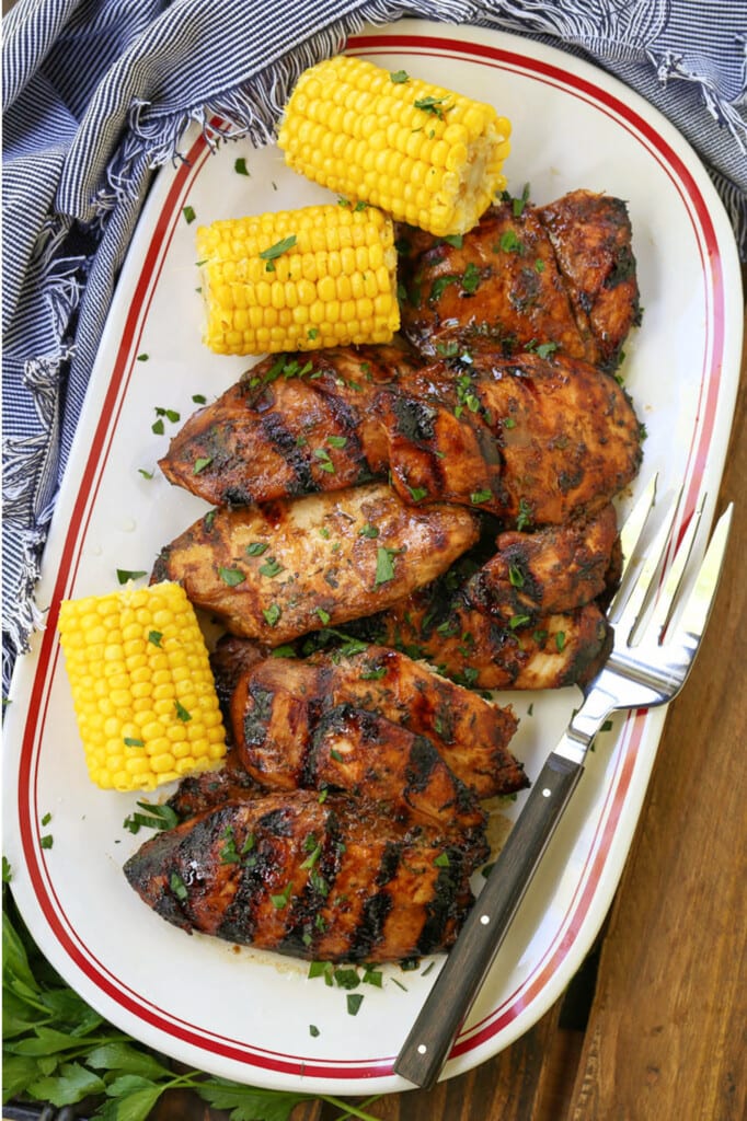 grilled chicken breasts on a platter with corn