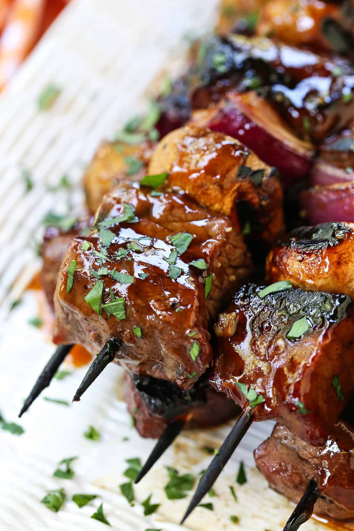 These Bourbon Steak Kabobs are always a hit! Grilled kabobs with tender steak and vegetables brushed with a brown sugar and bourbon glaze. steak kabobs with glaze stacked on platter