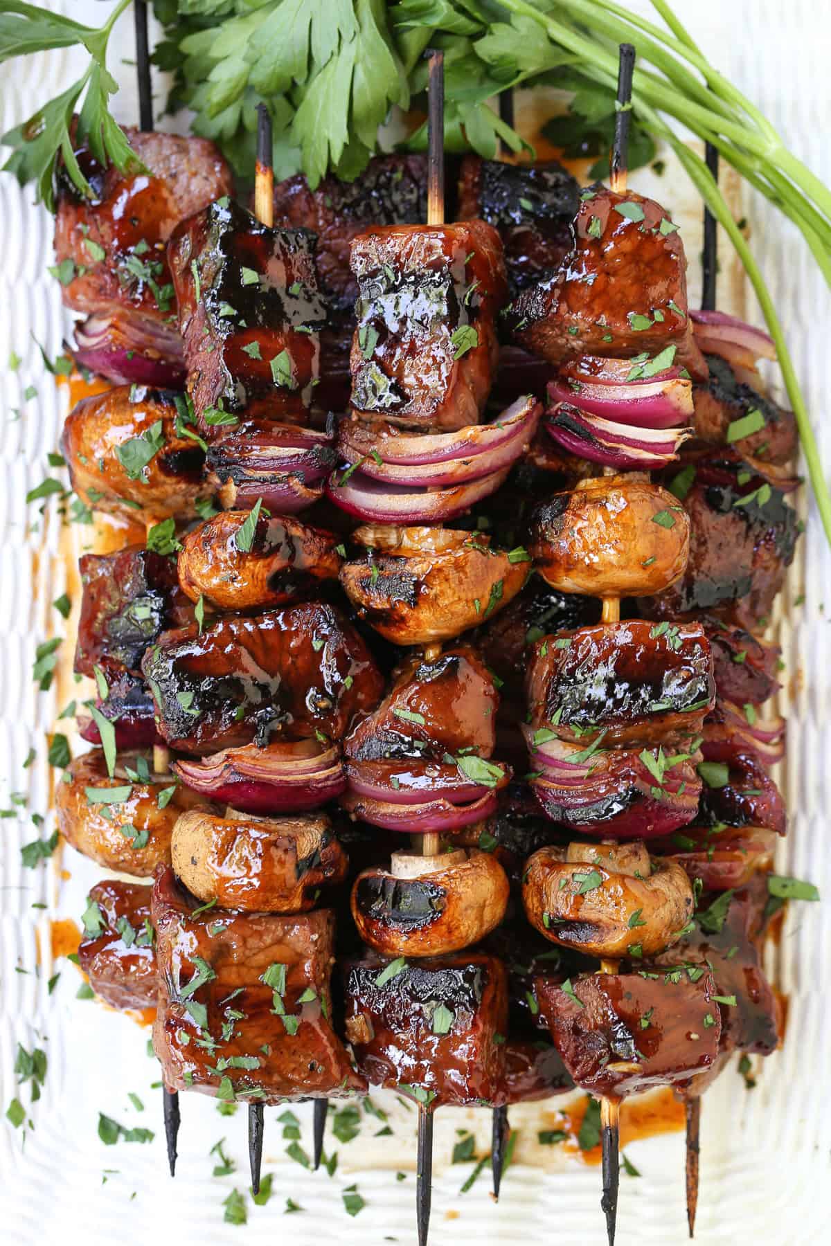 These Bourbon Steak Kabobs are always a hit! Grilled kabobs with tender steak and vegetables brushed with a brown sugar and bourbon glaze. Steak and vegetable kabobs stacked on white platter