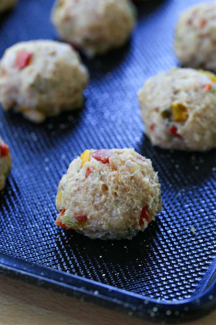 grond chicken meatballs with peppers on a baking sheet