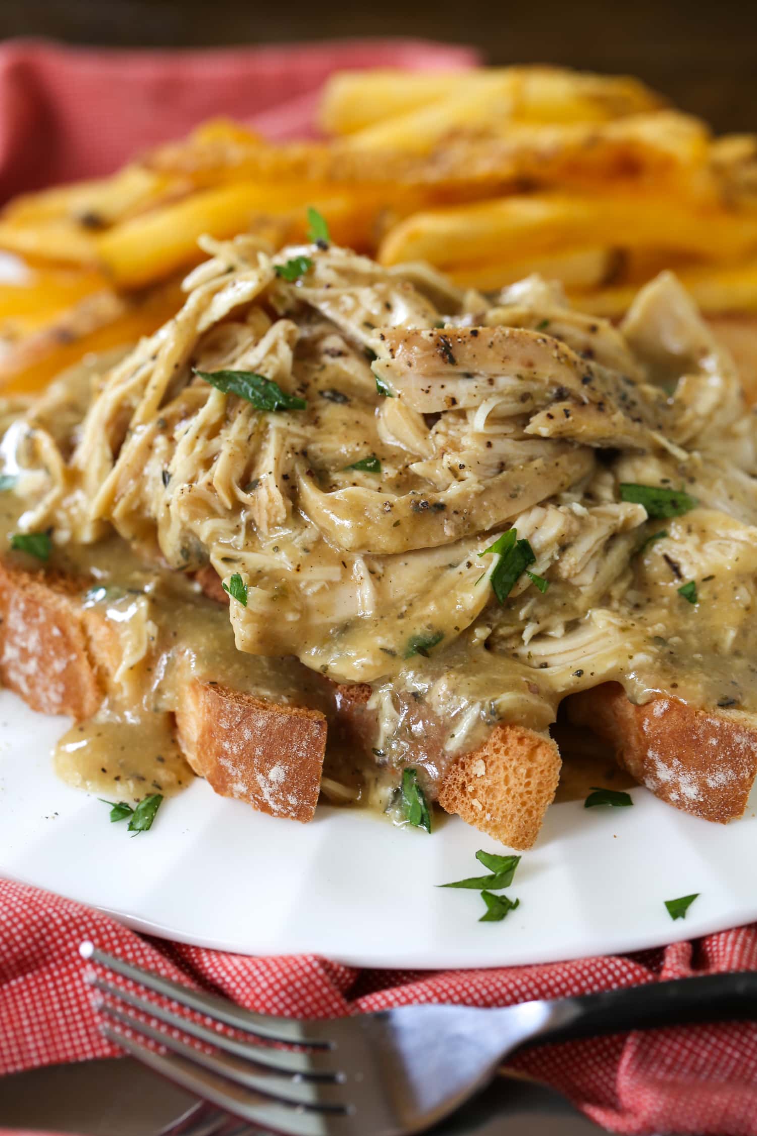 Craving a delicious, home-cooked meal but short on time? This easy recipe for Crock Pot Chicken and Gravy is sure to be a hit! shredded chicken and gravy served over toast with fries