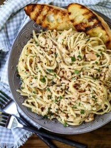 Linguine with clam sauce in a grey bowl with bread