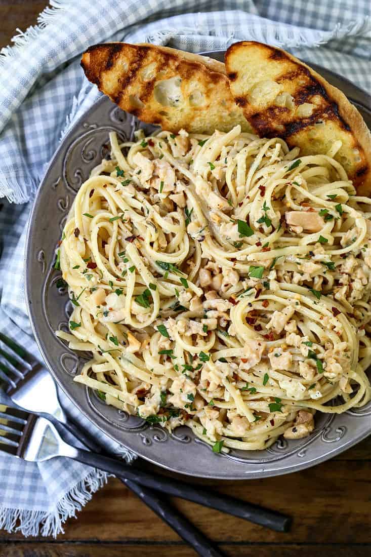 Linguine with clam sauce in a grey bowl with bread