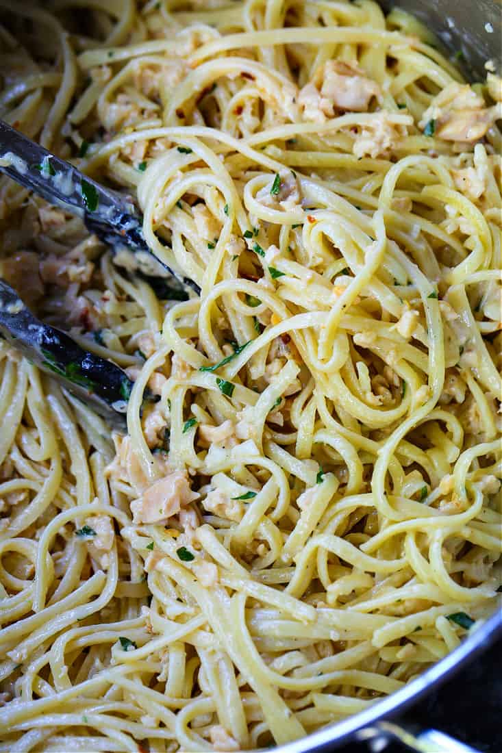 linguine with clams in a pot with tongs