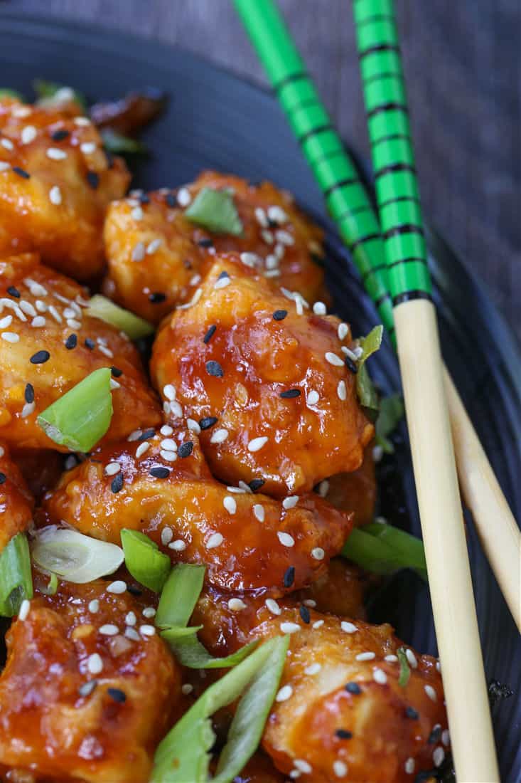 General Tso's Chicken on a black plate with chop sticks