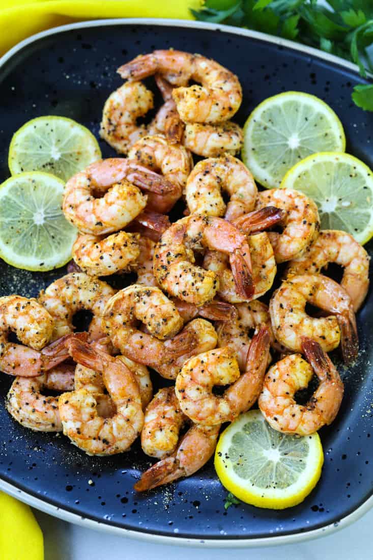 Air Fryer Lemon Pepper Shrimp on a black serving plate with lemon slices