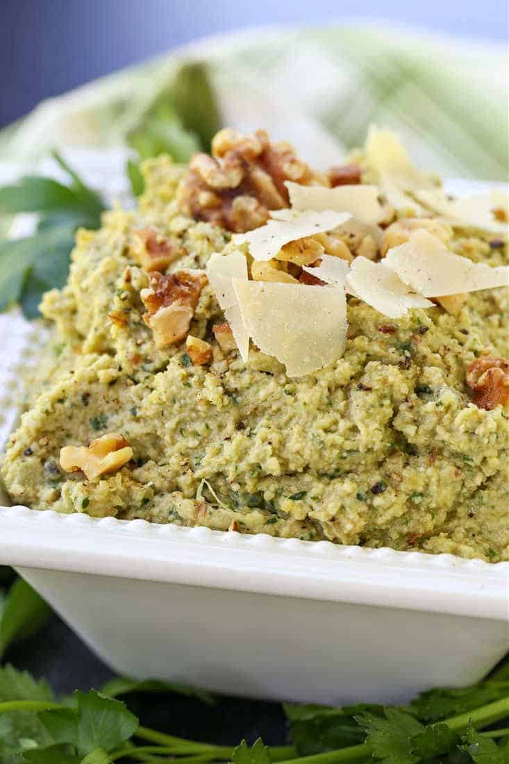 Artichoke walnut pesto in a white bowl with parmesan cheese