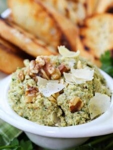 Pesto recipe with artichoke hearts, toasted walnuts and parmesan cheese in a serving bowl with toast