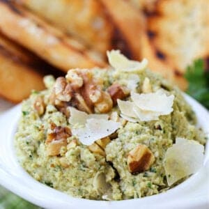 Pesto recipe with artichoke hearts, toasted walnuts and parmesan cheese in a serving bowl with toast