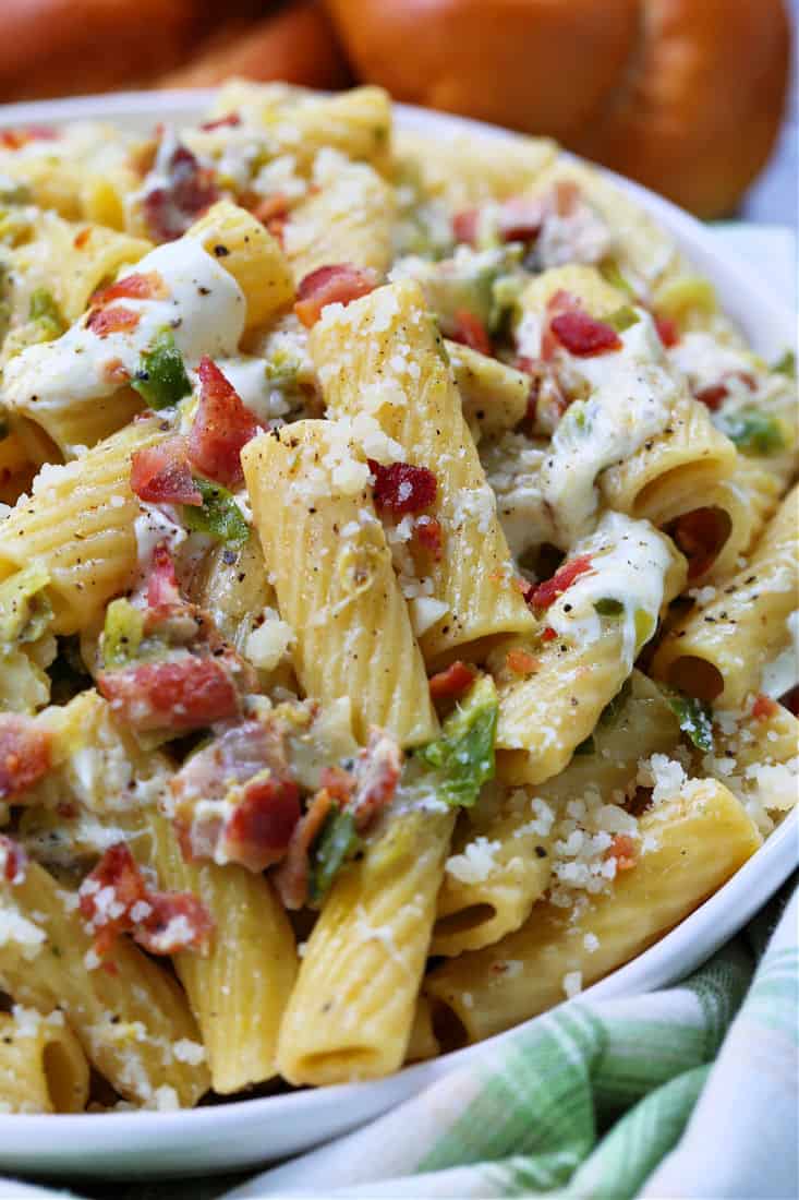 Pasta recipe with cheese, bacon and brussels in a white bowl