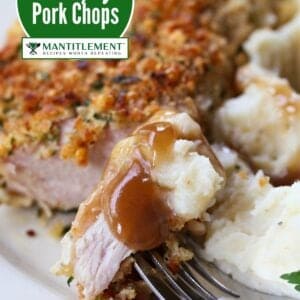 bite of pork chop on a fork with potatoes and gravy