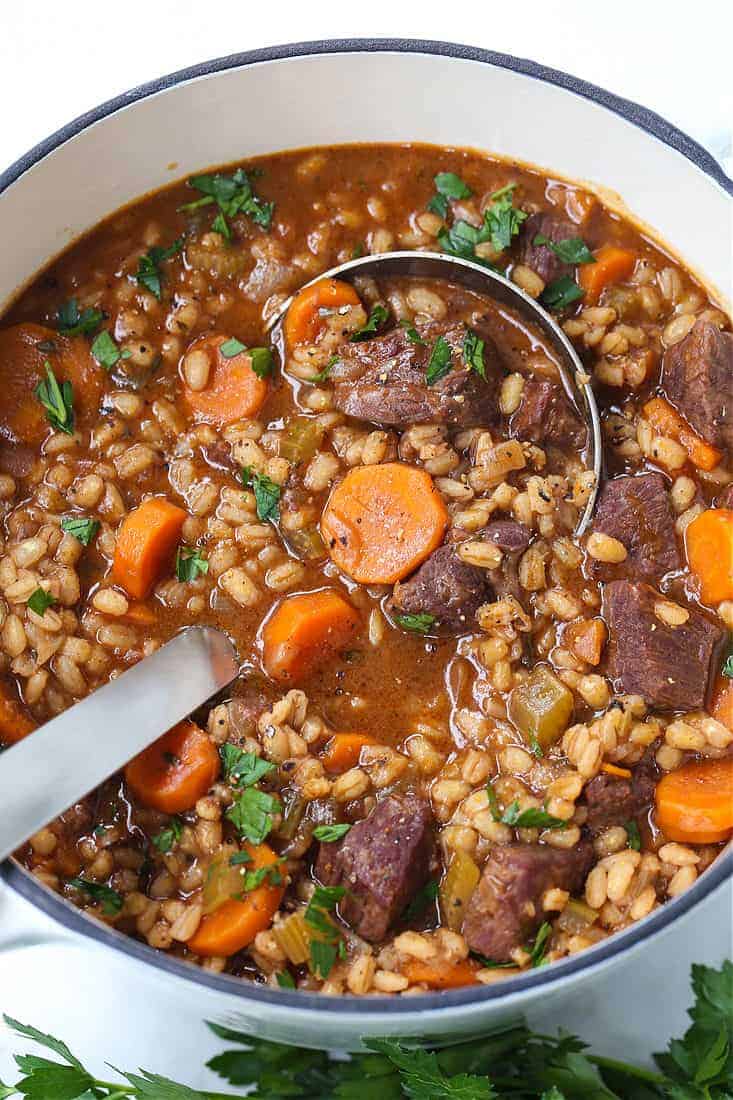 Beef Barely Soup in a pot with a ladle