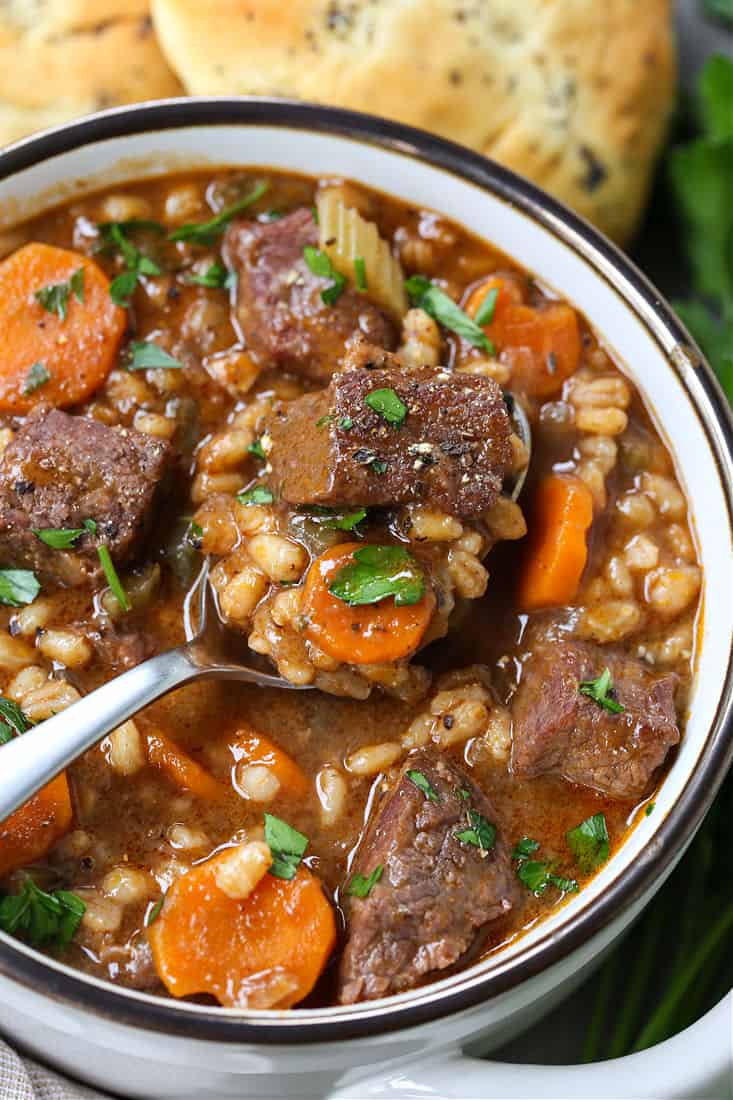 Beef soup recipe with barley and vegetables in a bowl with a spoon