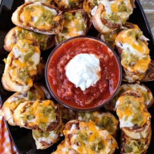 Mexican crostini on a platter with salsa and sour cream