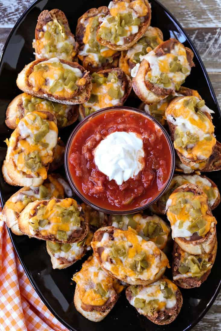 Mexican crostini on a platter with salsa and sour cream