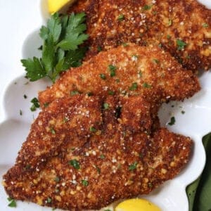 Breaded chicken cutlets with lemon wedges on a platter