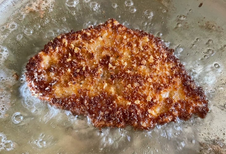 Breaded chicken cutlet frying in oil