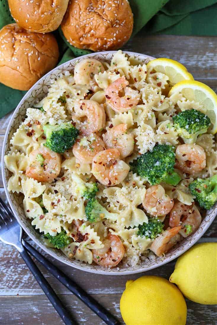 Pasta recipe with shrimp an broccoli in a bowl with rolls